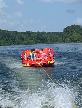 two children riding on a tubing gift for boaters on lake