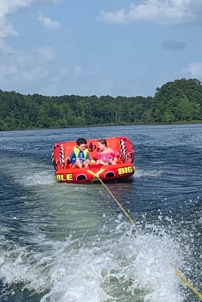 two children riding large tube float behind boat for ideas for gifts for boaters