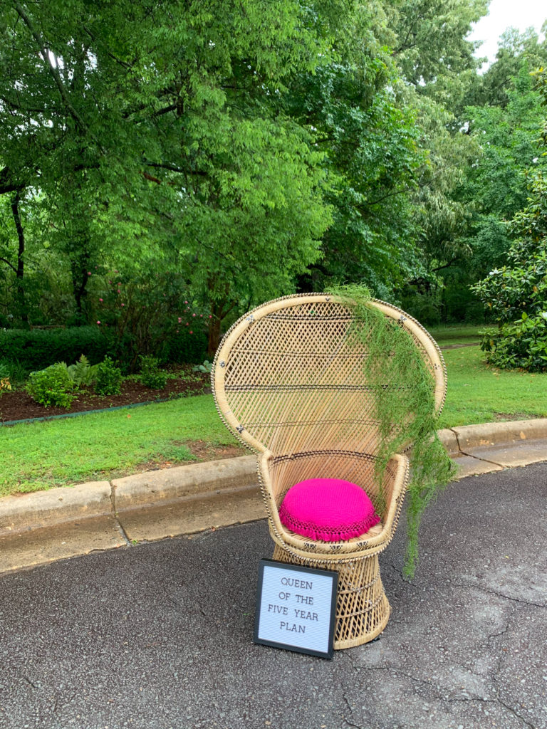 a vintage peacock chair with greenery and a letter board at a teacher retirement party