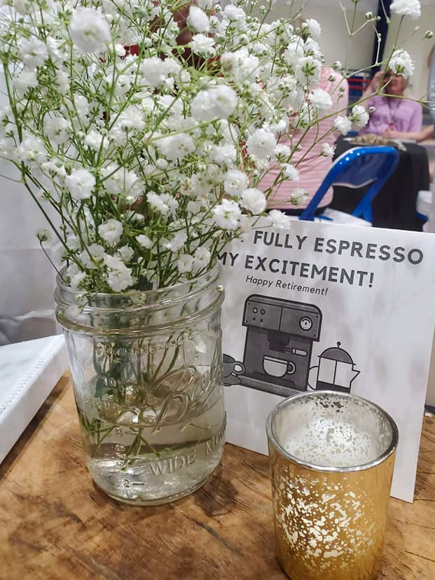 baby's breath in vase with a printed coffee quote and candle