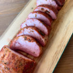 smoked pork tenderloin on light wood cutting board