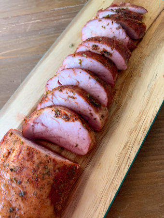 smoked pork tenderloin on light wood cutting board