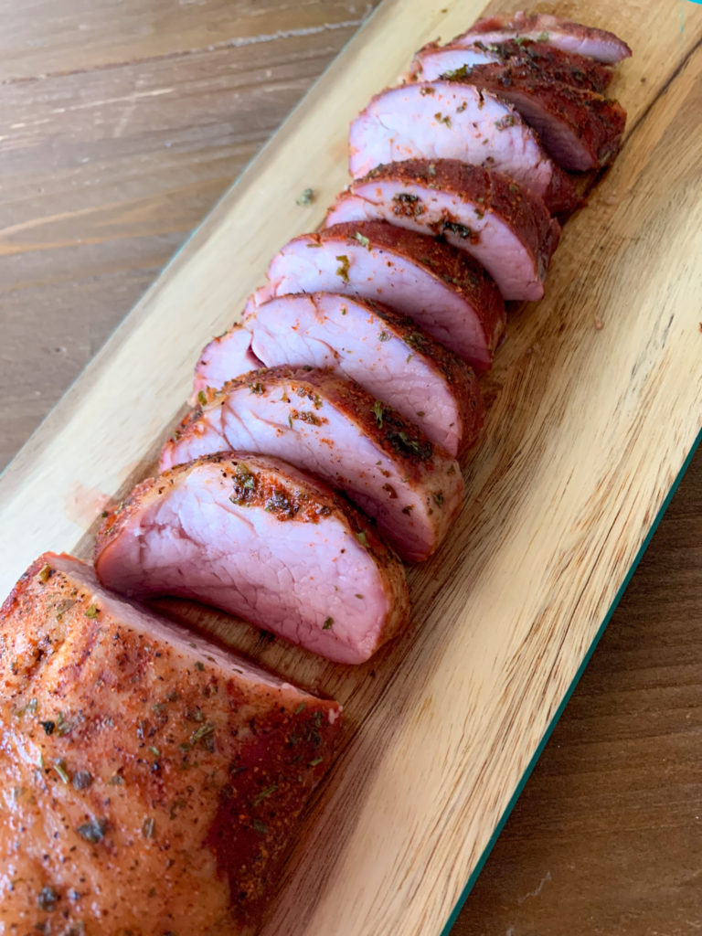 smoked pork tenderloin sliced on a wood cutting board