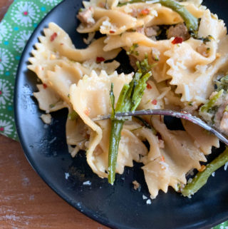 bowtie pasta with sausage and broccolini on black plate