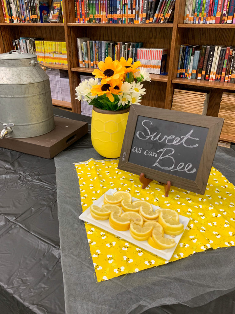 sunflower and bee baby shower display with a plate of lemons, a yellow pot of flowers, and a sign - for honey bee baby shower 