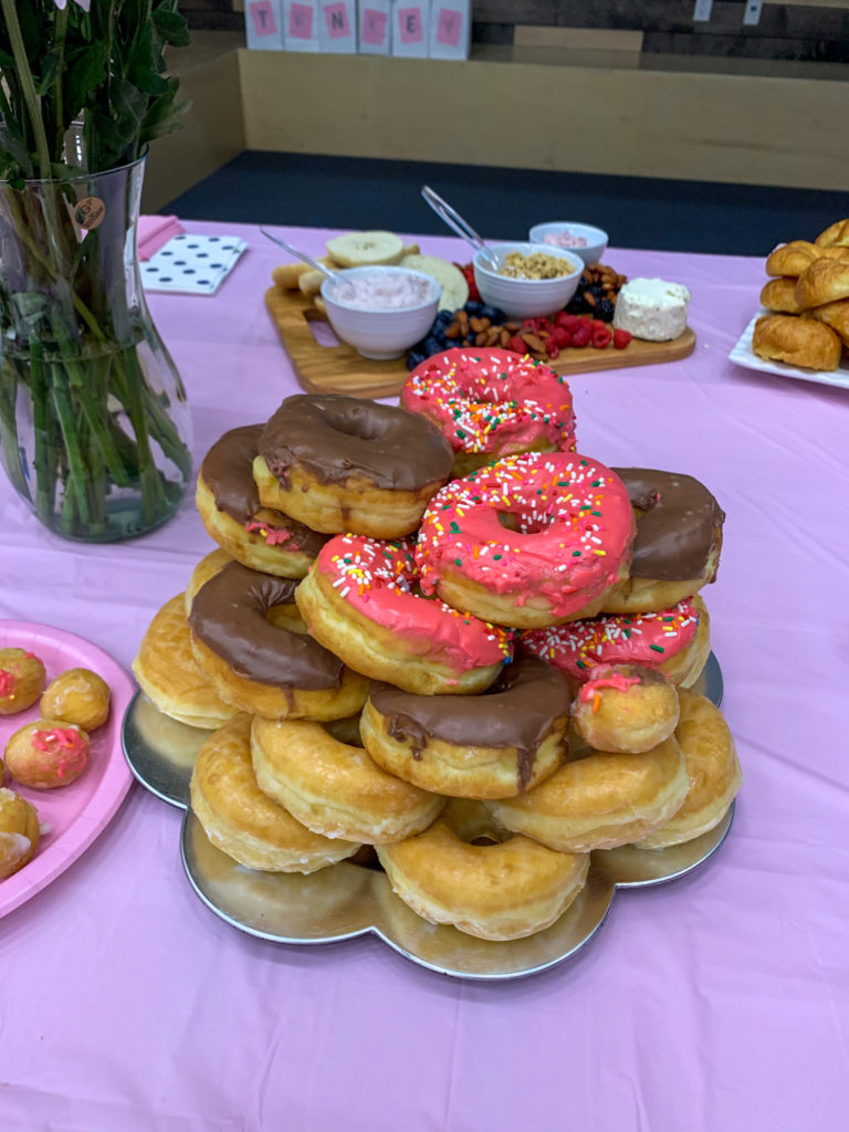 donut tower on pink tablecloth at breakfast baby shower
