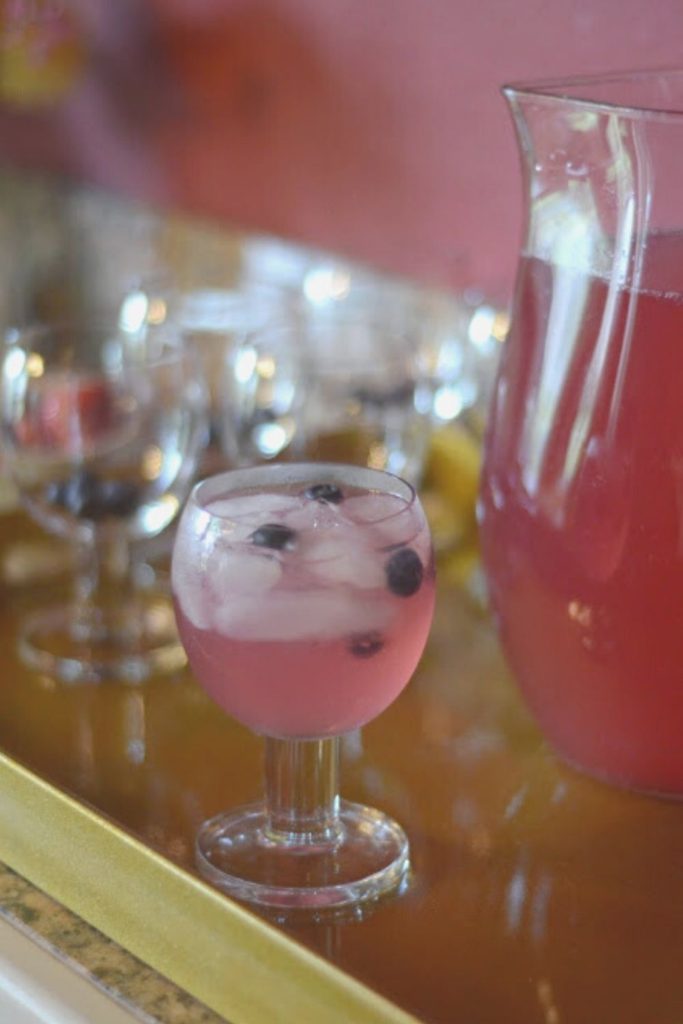 glass of iced Simply blueberry lemonade with Prosecco punch in front of pitcher