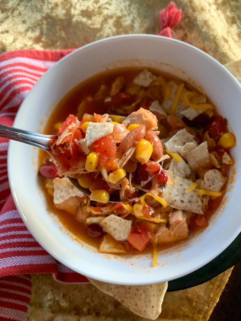30 minute chicken tortilla soup in white bowl with red napkin underneath