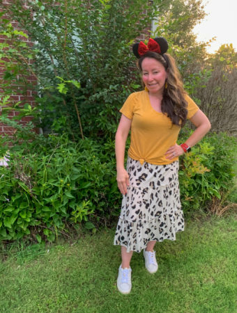 woman wears Disney Animal Kingdom outfit idea with leopard skirt and yellow shirt