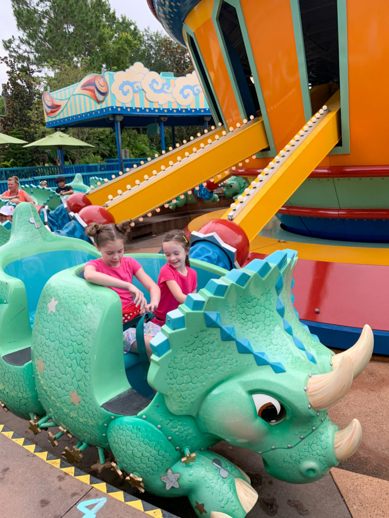 two girls ride the Triceratops ride at Animal Kingdom while wearing dinosaur skirts