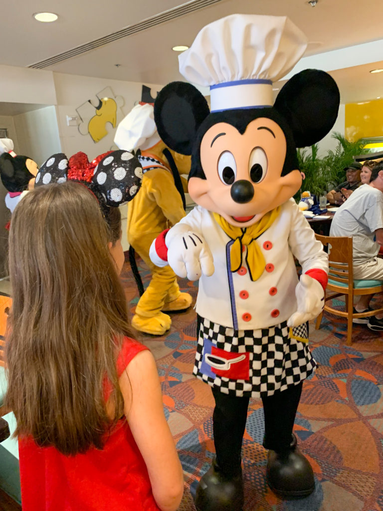 Mickey Mouse approaches girl at Chef Mickey breakfast at Disney World
