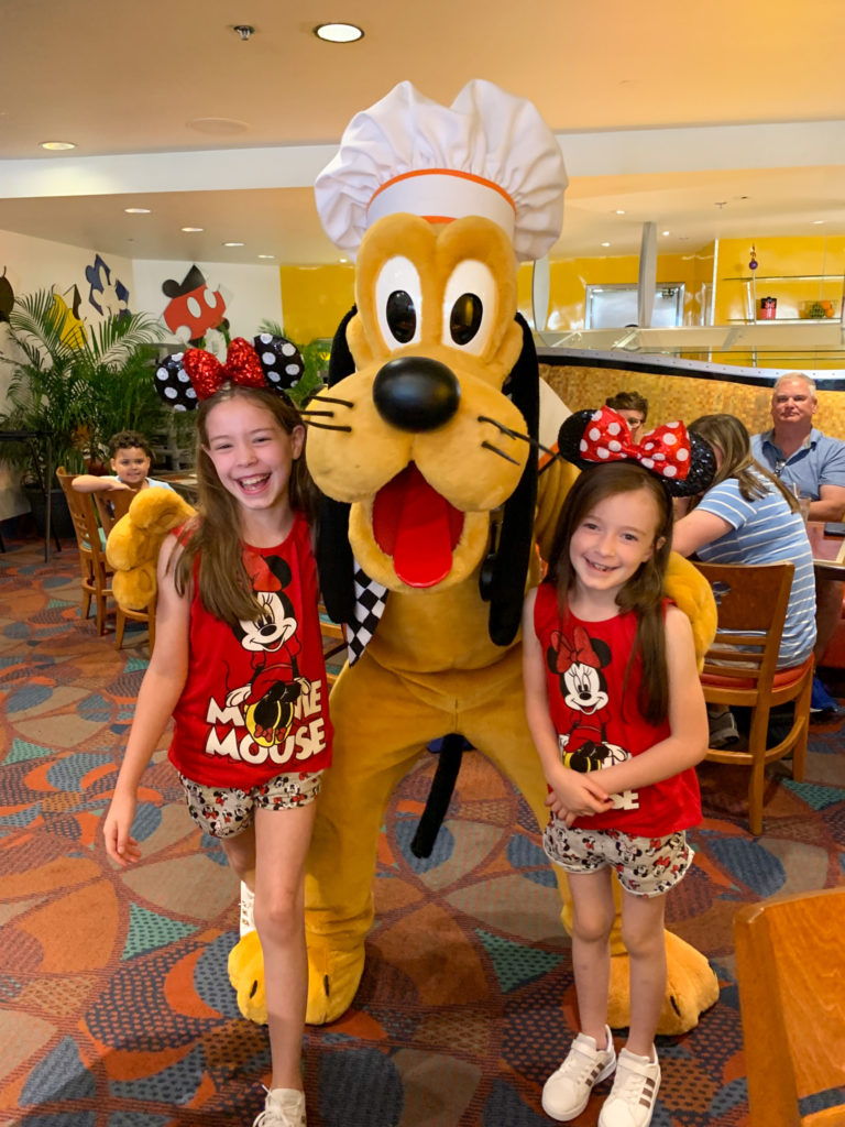 two girls with Pluto at Chef Mickey breakfast character meal 