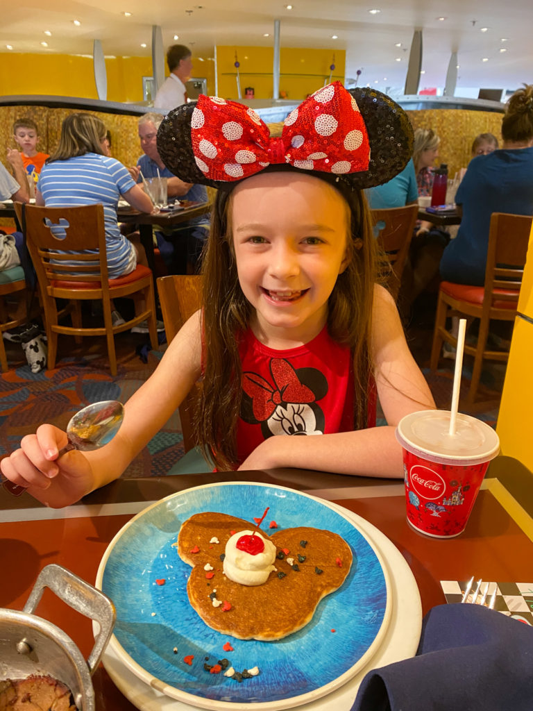 little girl with Mickey pancake at Chef Mickey character breakfast at Disney World