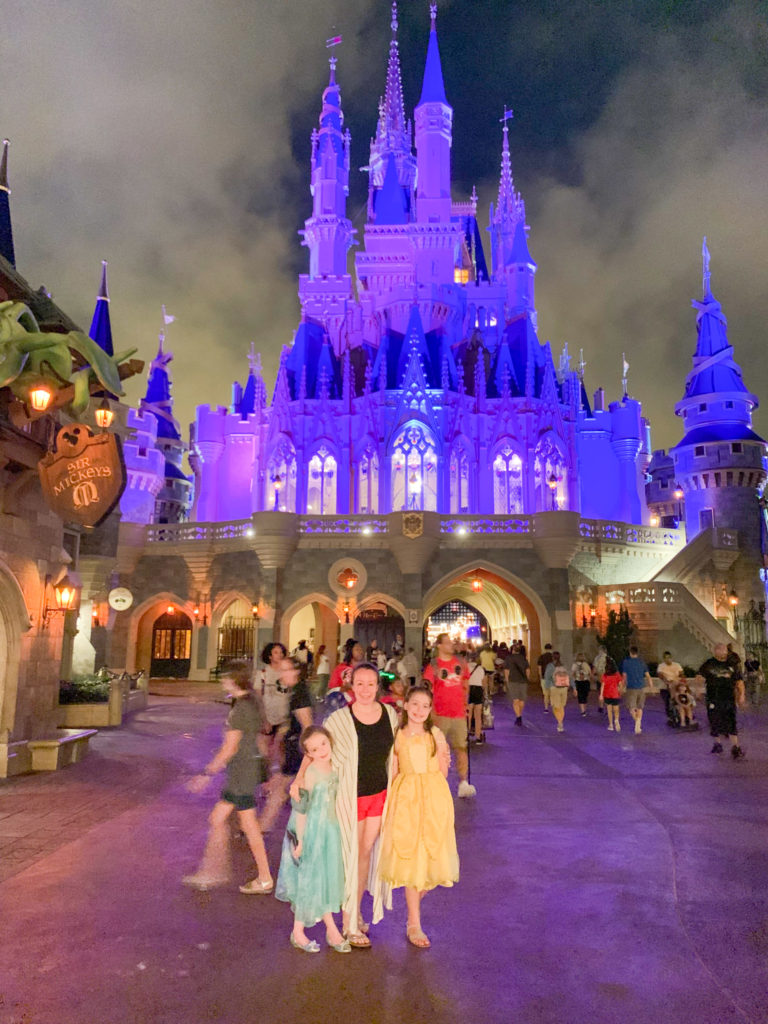 Amy of The Gifted Gabber (Planted in Arkansas) and daughters stand in front of Magic Kingdom castle at night