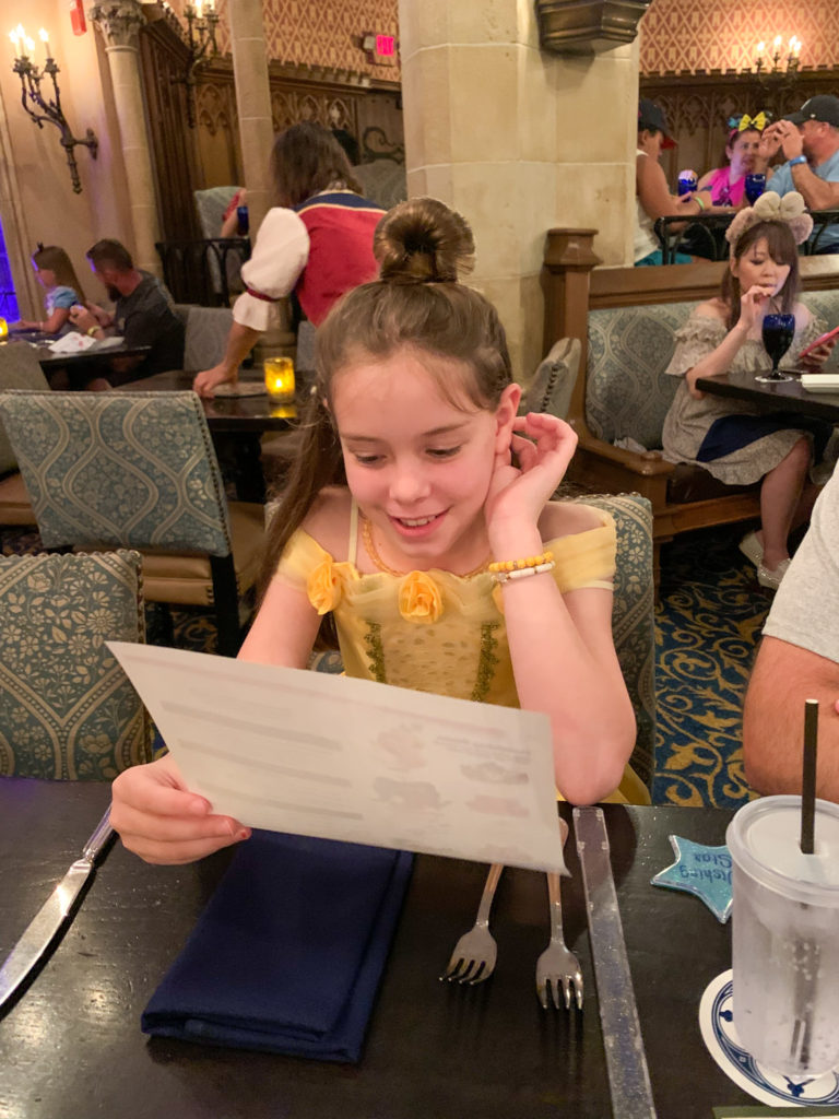 little girl looking at menu at Cinderella's Royal Table at Magic Kingdom 