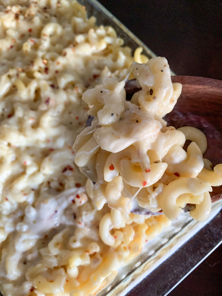 glass pan of pepper jack mac and cheese with wooden spoon 