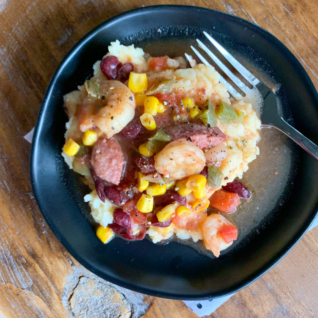 spicy corn and shrimp stew with sausage over mashed potatoes