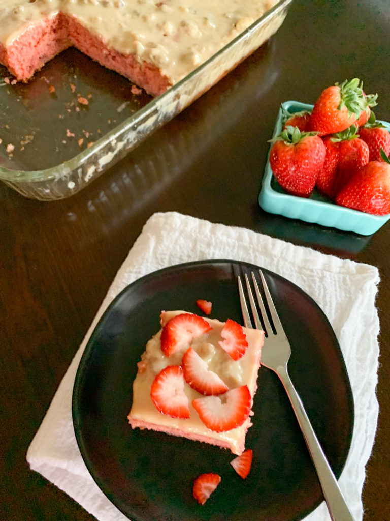 banana strawberry cake with blue basket of strawberries and pan of cake in background