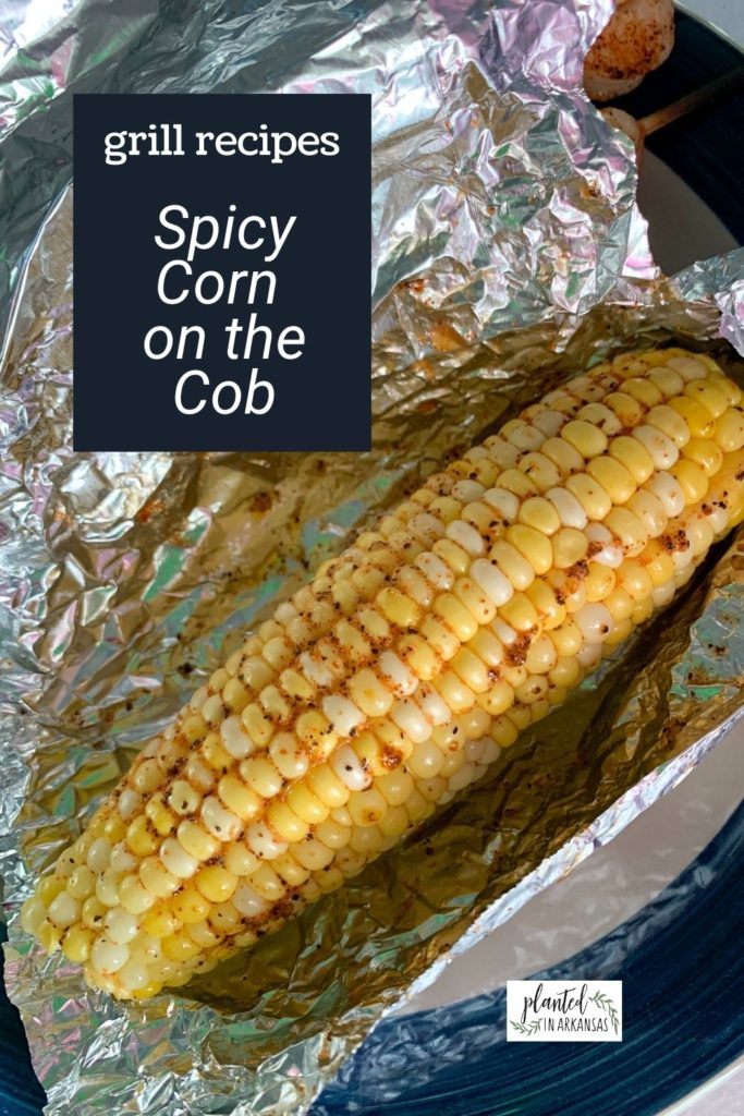 plate of spicy corn on the cob grilled in foil with a text overlay