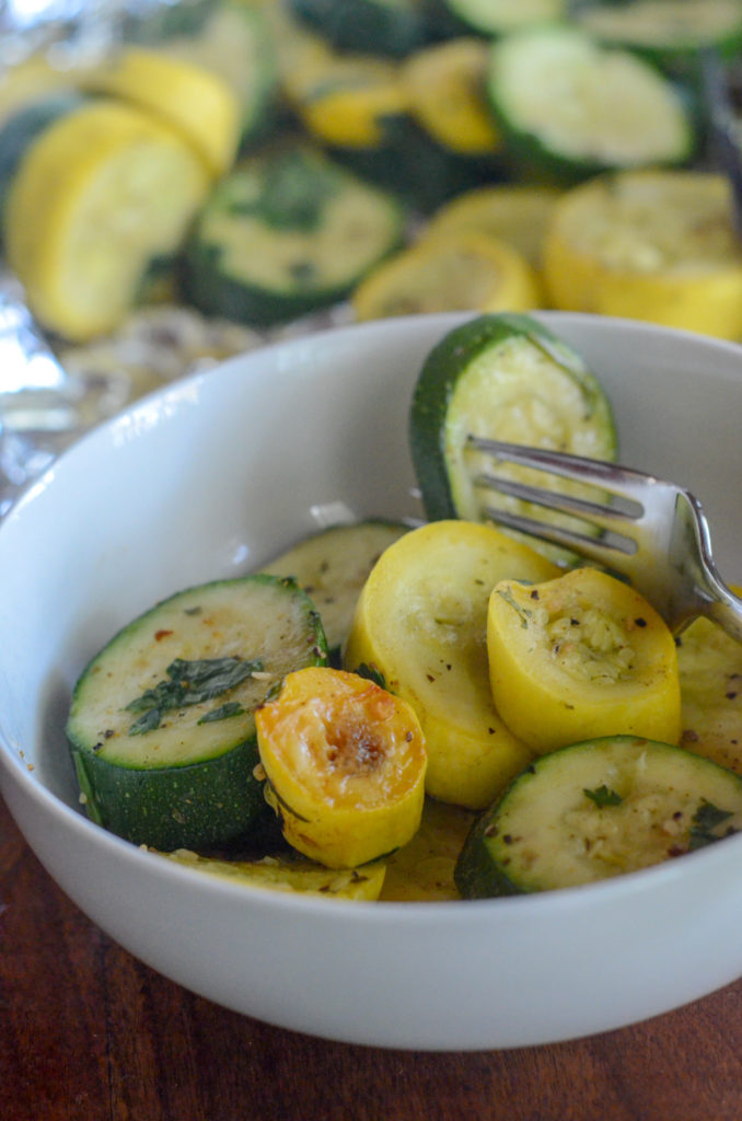 white bowl of oven baked zucchini and squash with silver fork