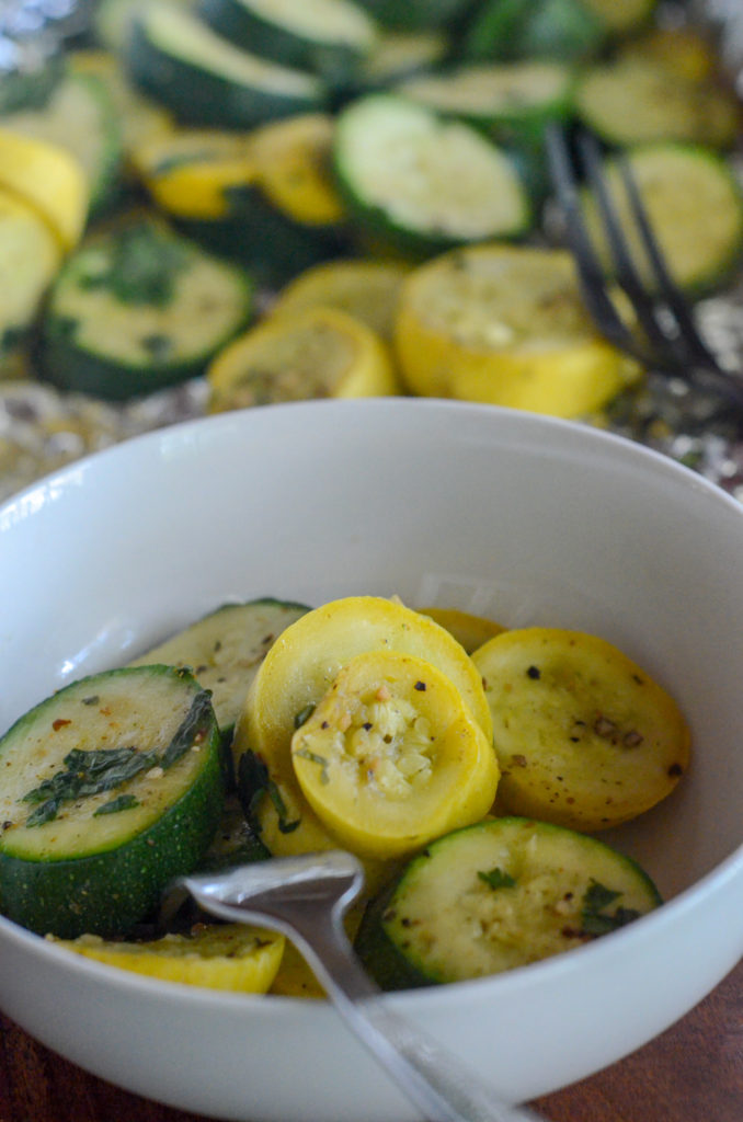 white bowl with grilled zucchini and squash in foil packet in back ground