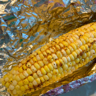 spicy grilled corn on the cob grilled in foil on top of plates