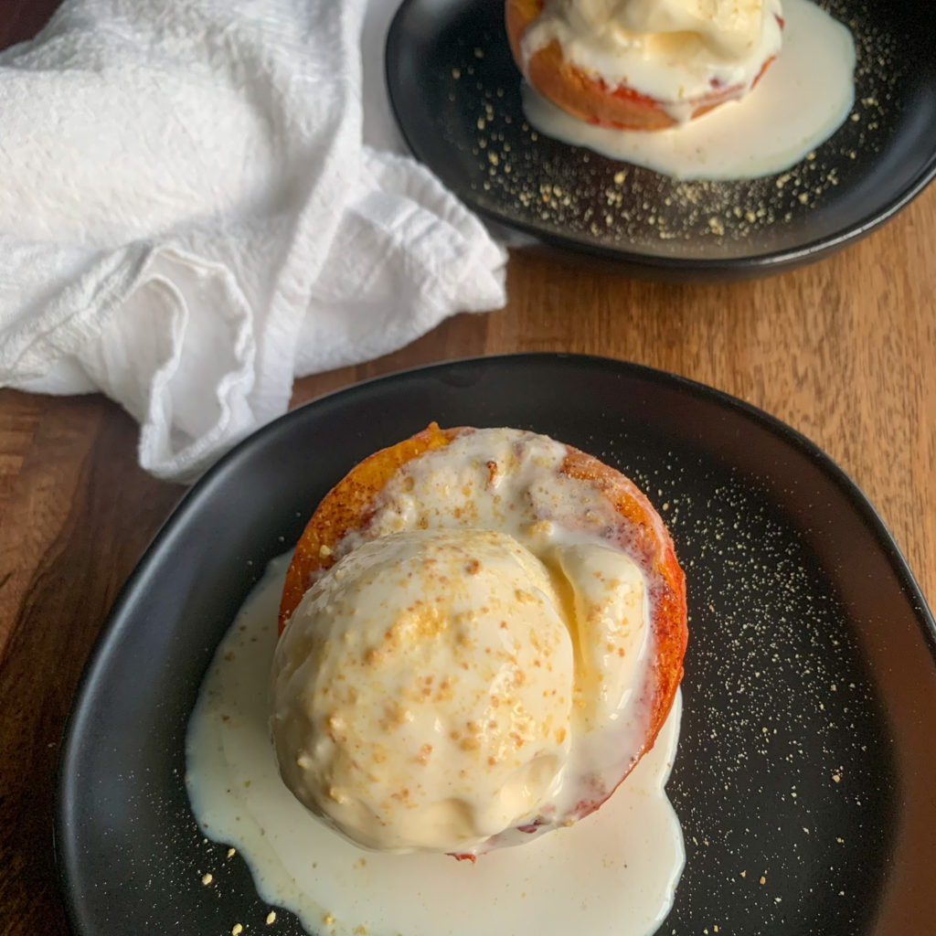 air fryer peaches on black plates with ice cream on top