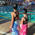 girls stand in front of competition pool at kids swim team meet event