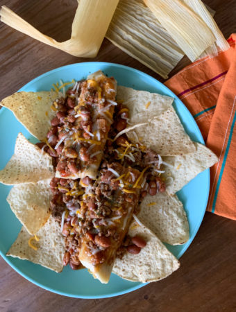 smothered tamales with chili on blue plate