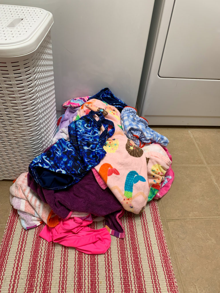pile of swim team laundry in laundry room floor