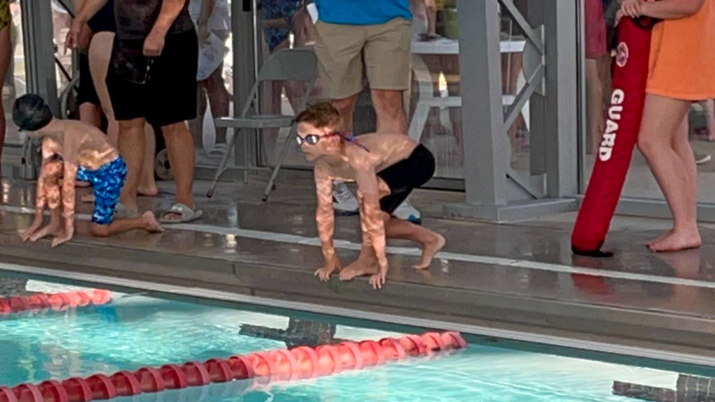 little boy in position for a swim meet heat