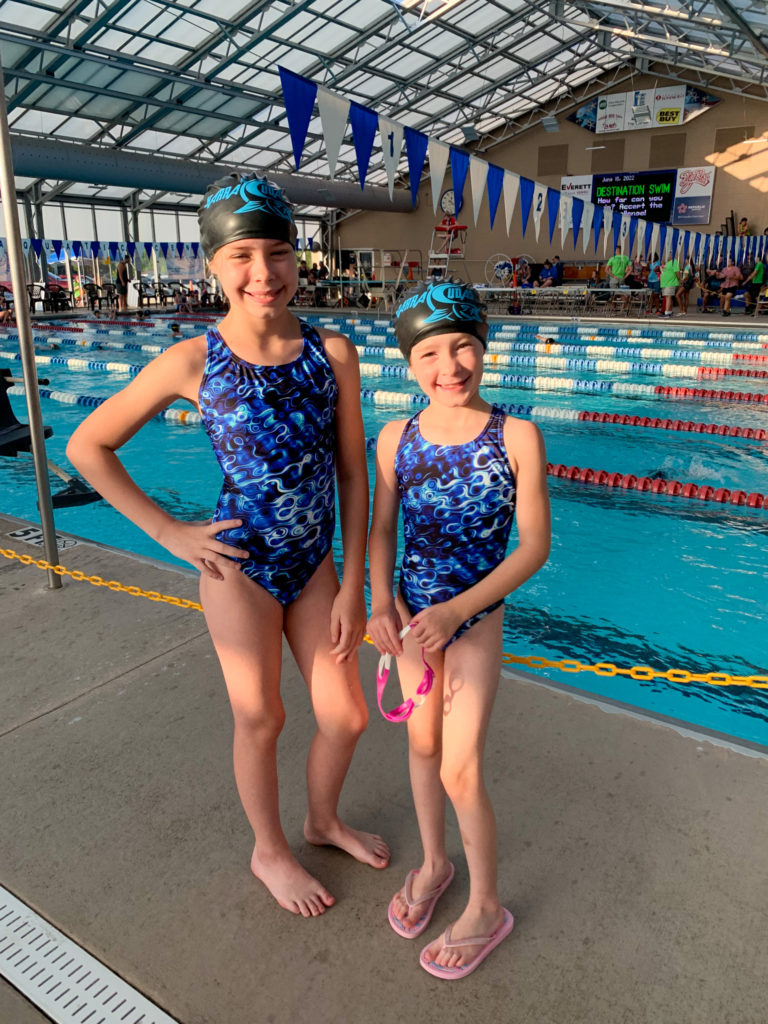 girls pose in swim team swimsuits at a kids swim team practice