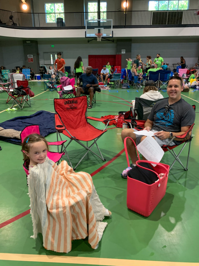 daughter and dad wait in lawn chairs in gym of a youth swim meet event
