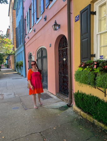 woman in pink dress walking on Rainbow Row in Charleston on a girls weekend to Charleston trip
