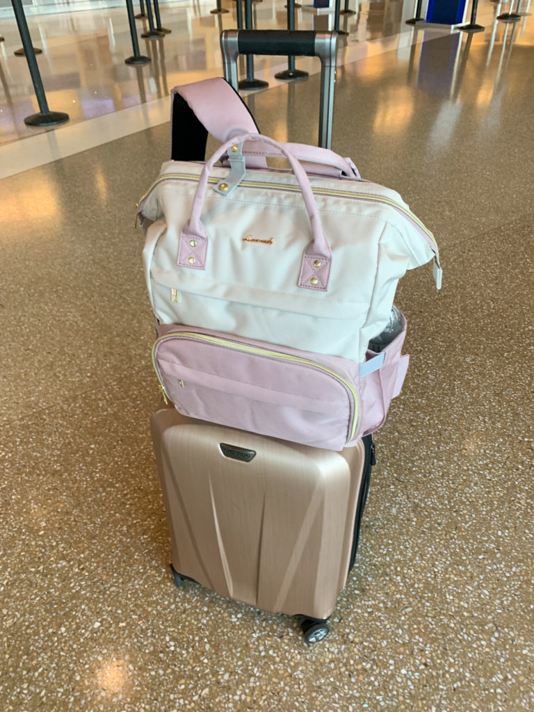 best teacher backpack with many compartments on top of rose gold rolling carry on luggage