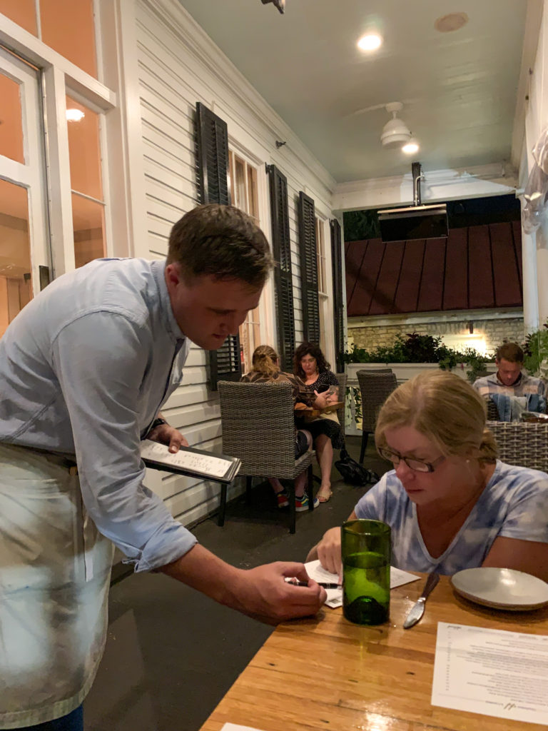 waiter helps woman with menu at Husk Restaurant