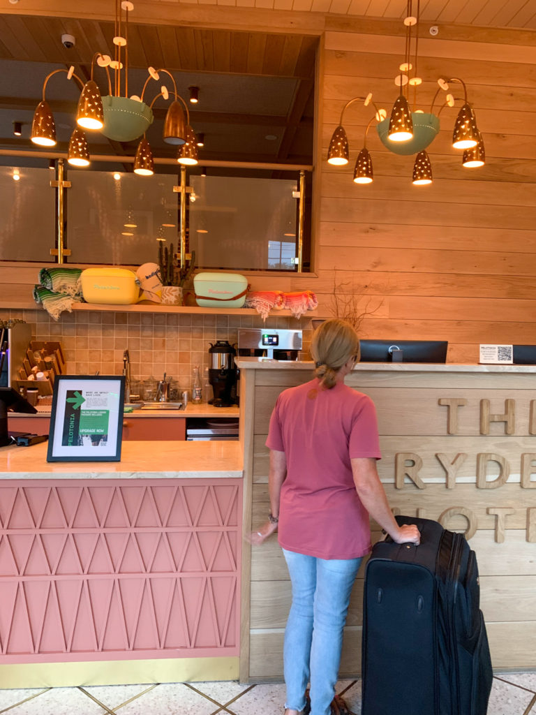 woman stands at front desk with suitcase at The Ryder Hotel in Charleston