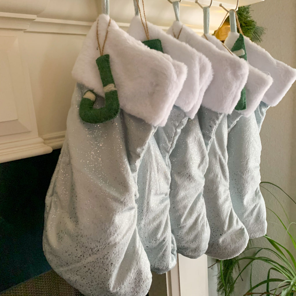 ice blue sparkle stockings with green felt initial letters on holiday mantel