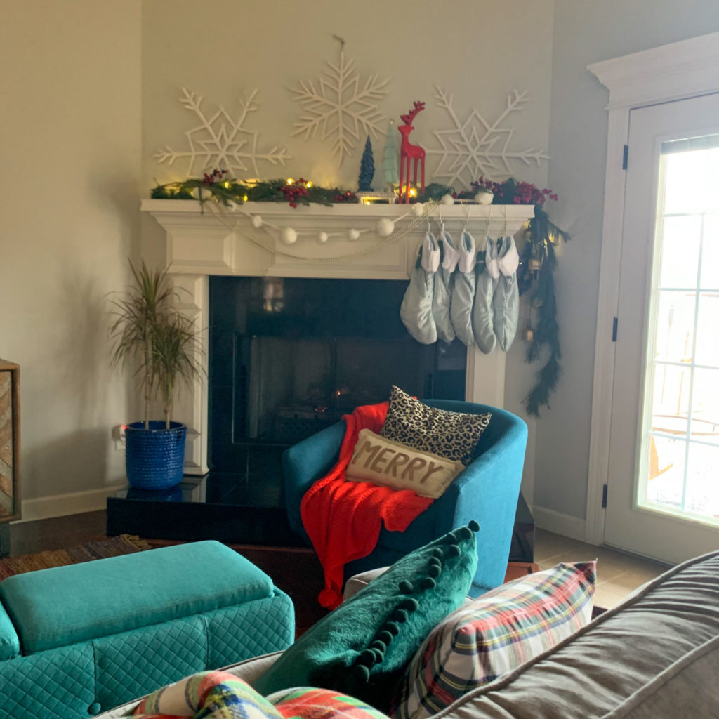 Blue and red Christmas decor in living room with snowflake mantel and sofa in Christmas plaid pillows
