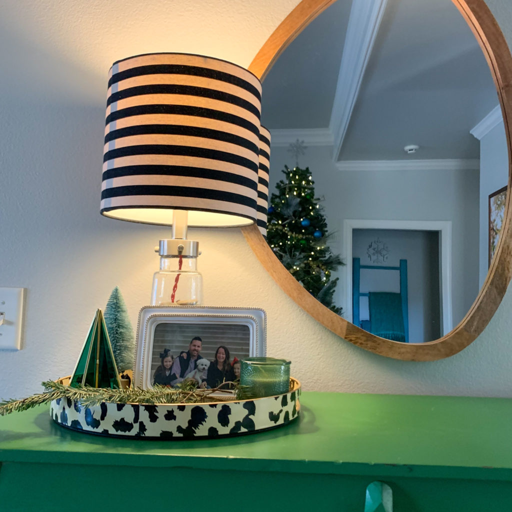 green shelf with oblong mirror and striped lamp shade