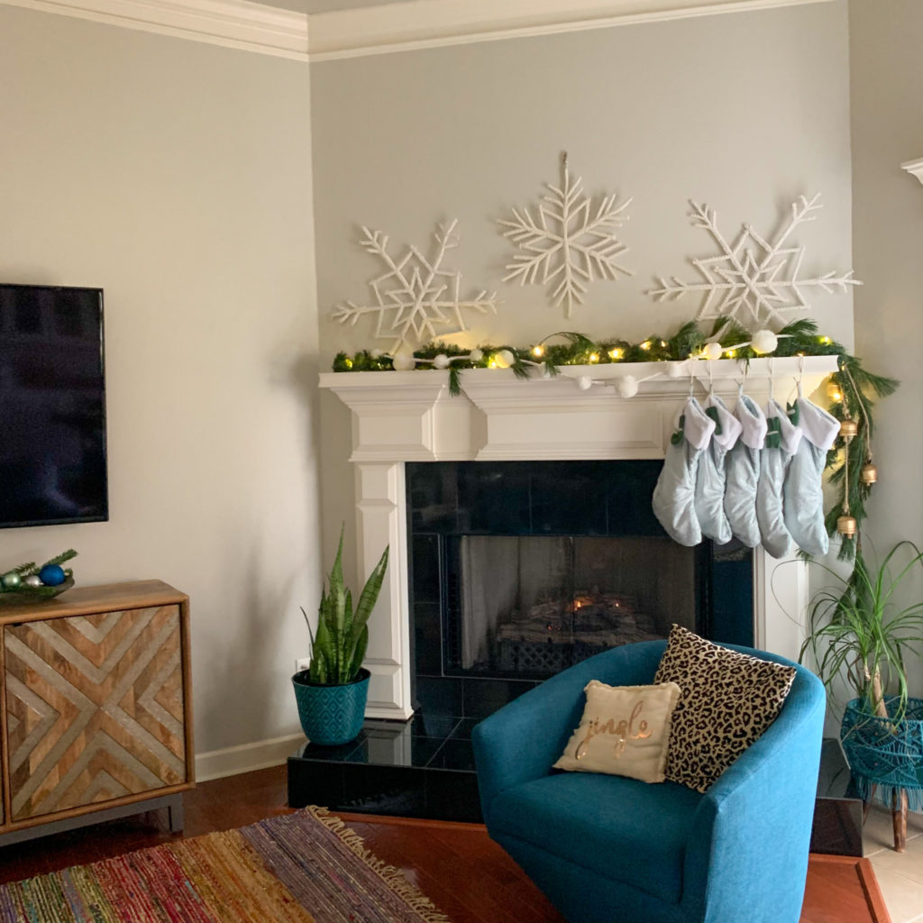 a Christmas snowflake mantel with blue Christmas decorations and a blue swivel chair