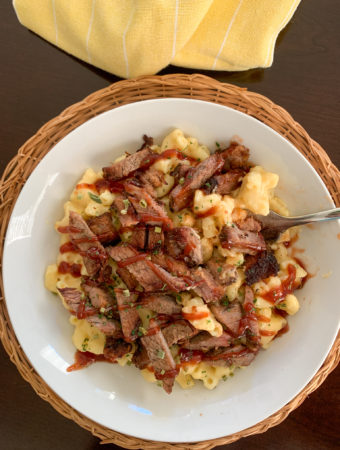 white plate of brisket mac and cheese with yellow napkin to side