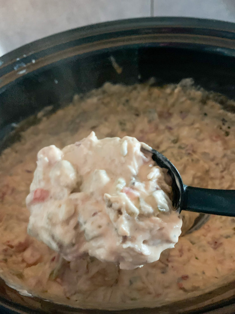 slow cooker view of pulled pork dip on black serving spoon