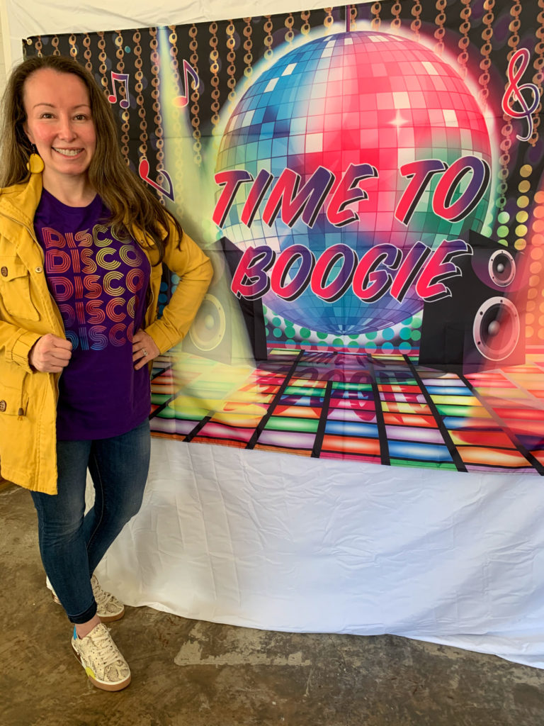woman wears Disco t-shirt in front of a disco banner