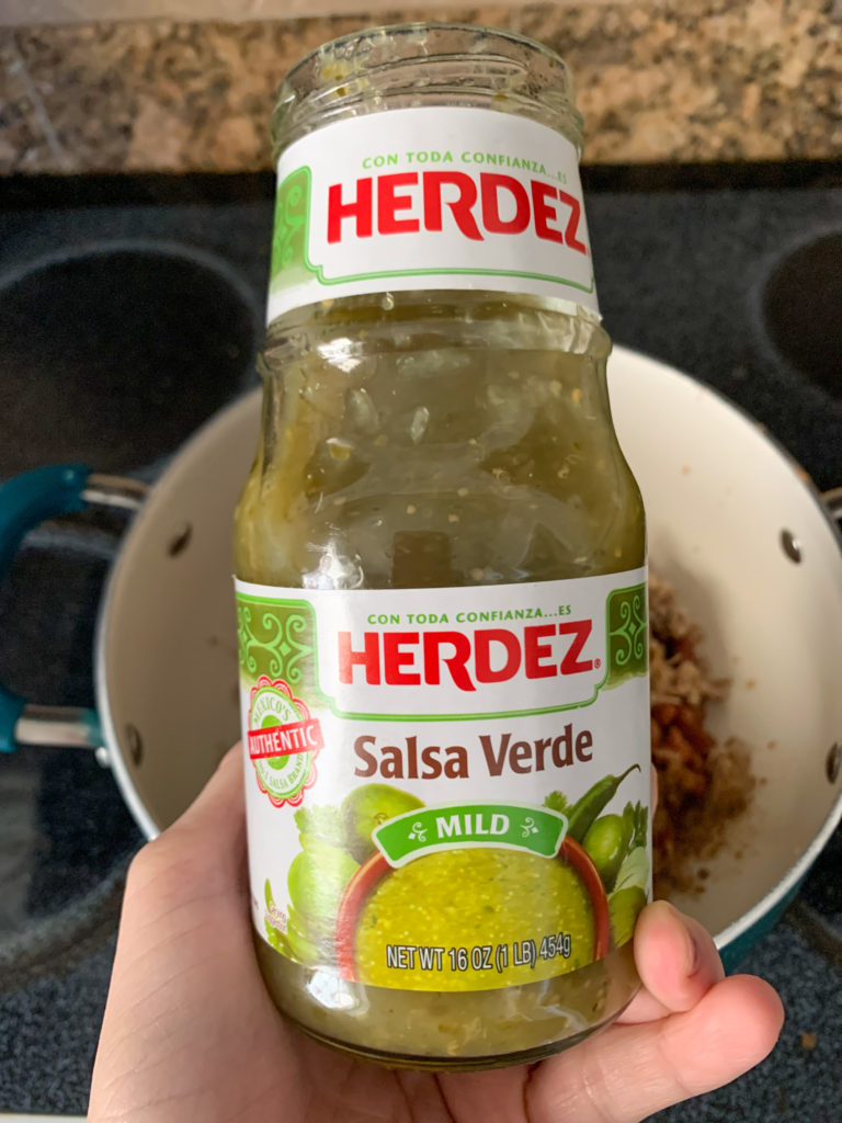 woman holds bottle of Herdez salsa verde for recipe