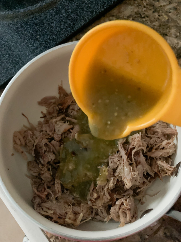 salsa verde poured from cup into meat in pot