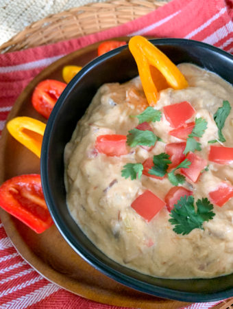 spicy queso dip in black bowl with bell pepper dippers