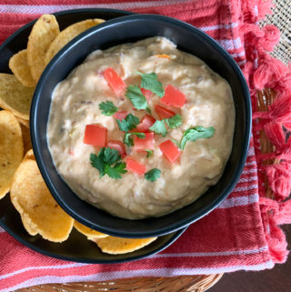 spicy queso dip with meat and Fritos around on red towel