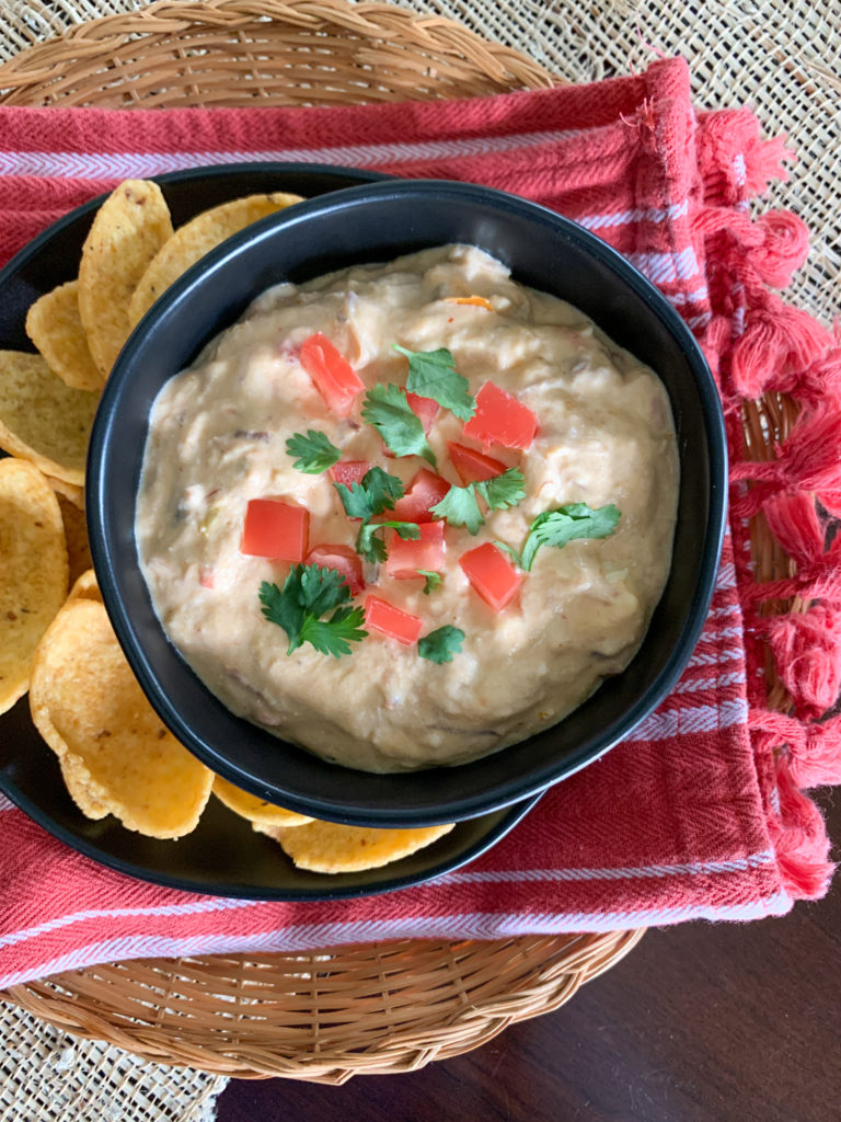 spicy queso dip in black bowl with fritos