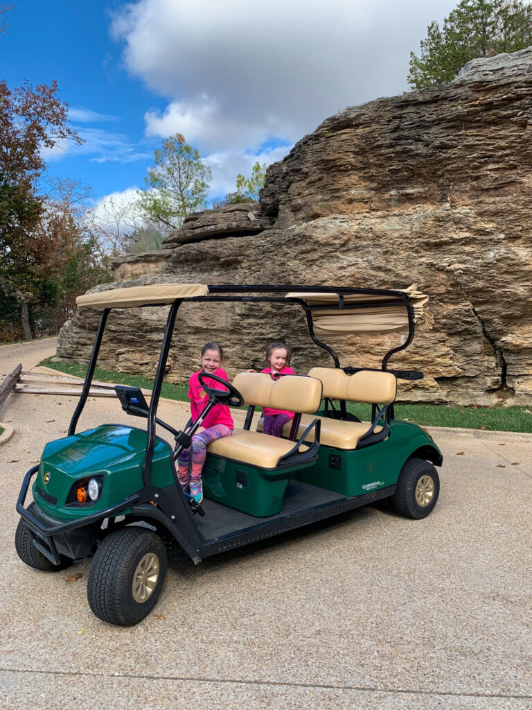 two girls in golf cart on the Big Cedar Top of the Rock golf cart tour to explore Lost Canyon Cave 